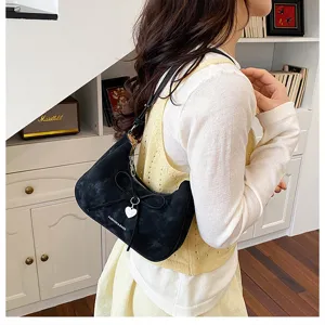 Vue détaillée d'un sac à nœud noir avec charm cœur porté par un modèle