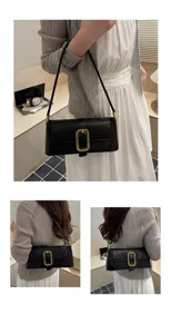 Fashionable black crocodile texture baguette bag with a large gold chain buckle detail.