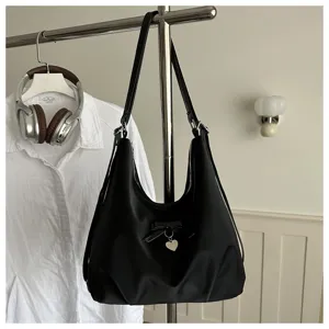 Black casual hobo bag with bow and heart pendant hanging on a metal rack