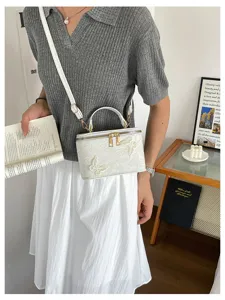 Vista dettagliata della borsa a scatola bianca con ricami di farfalle e trama jacquard