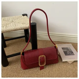 Detailed view of the red crocodile embossed texture on a French baguette shoulder bag