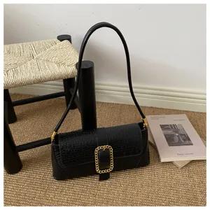 Detailed macro view of a black croc-pattern baguette underarm bag with a gold buckle.