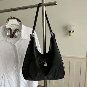 Versatile black large capacity hobo bag featuring bow detail and a heart pendant charm