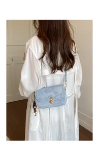 Sac à bandoulière bleu clair texturé avec fermoir en métal sur un modèle de dos
