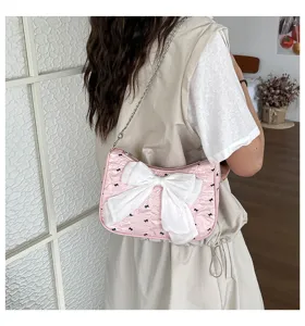 Stylish pink seersucker armpit bag featuring a large white bow and silver chain strap