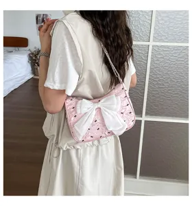 Close-up detail of a pink bubble gauze tote bag with a large white bow and chain strap