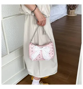 Pink bubble gauze shoulder bag with large white bowknot shown carried by hand