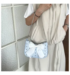 Detail view of light blue seersucker shoulder bag with oversized white bow decoration