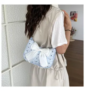 Close-up detail of a light blue bubble gauze underarm bag featuring a large white bow