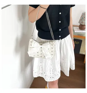 Detail view of a stylish white bubble gauze shoulder bag with a large bow decoration
