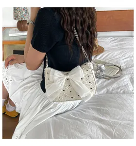 Close-up of elegant cream seersucker shoulder bag with large white bow and chain strap