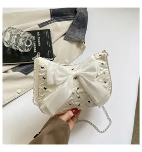 Detail view of a cream bubble yarn shoulder bag featuring an elegant oversized silk bow