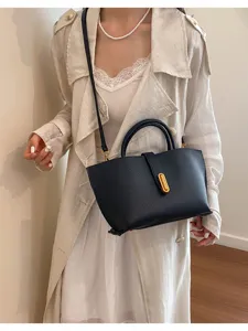 Vista detallada de un bolso tote retro de cuero negro llevado por una modelo con gabardina
