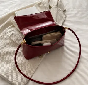 Detailed view of red patent leather underarm bag showing spacious interior capacity.