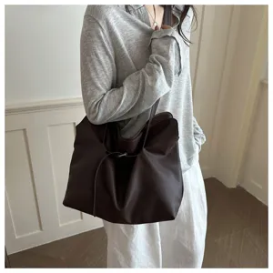 Large dark brown leather tote bag with minimalist design carried by a model on shoulder