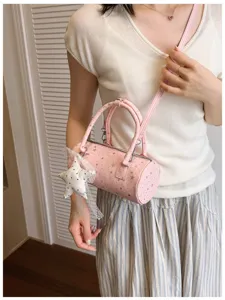 Vue détaillée d'un sac cylindrique rose avec des étoiles d'argent et un charme