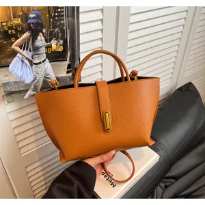Detalle de un bolso tote de cuero marrón con un elegante cierre de metal dorado