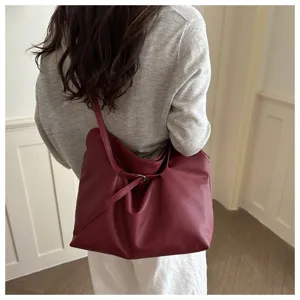 Back view of model carrying a large burgundy leather tote bag in a minimalist style