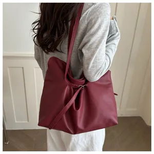 Model wearing a large burgundy leather tote bag with a minimalist slouchy design for commuting