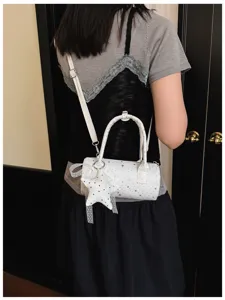 Détail d'un sac polochon blanc à motifs d'étoiles porté par un mannequin en situation.