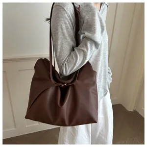 Large brown pebbled leather tote bag worn as a commuter shoulder bag in minimalist style