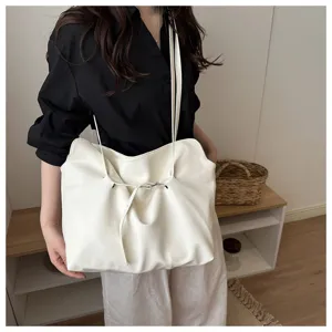 Minimalist white faux leather tote bag being carried by a woman in a casual setting