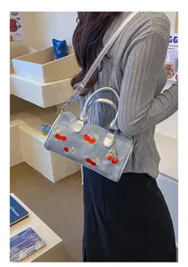 Lifestyle view of cherry embroidered denim Boston bag with shoulder strap