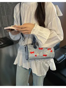 Detailed view of embroidered cherry denim Boston bag worn with casual outfit.