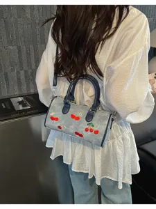 Stylish blue denim Boston bag featuring detailed embroidered cherry patterns for women