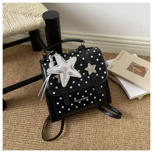 Nahaufnahme eines schwarzen Mini-Rucksacks mit Polka-Dots und silbernem Sternenanhänger