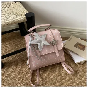 Lifestyle-Detailansicht eines modischen rosa Polka-Dot-Rucksacks mit silbernen Sternanhängern