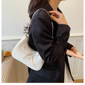 Vue détaillée du sac hobo blanc élégant avec nœud papillon et charmant pendentif cœur
