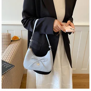 Élégant sac à main bleu clair avec nœud papillon porté par un mannequin dans un cadre moderne.