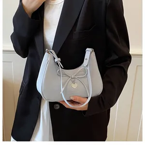 Détail du sac à main croissant bleu clair avec nœud et pendentif en forme de cœur