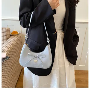 Gros plan d'un sac hobo bleu clair élégant avec un nœud et un pendentif cœur