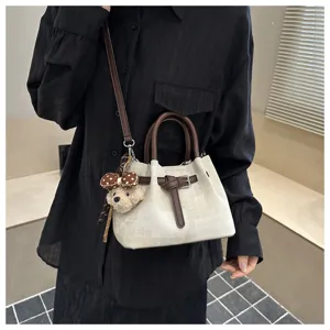 Vintage canvas and leather bucket bag with cute bear charm shown as crossbody style