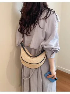 Vue détaillée d'un sac en paille tressée en forma de croissant avec garniture en cuir noir.
