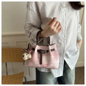 Detailed view of a pink checkered handheld bucket bag featuring a plush teddy bear charm