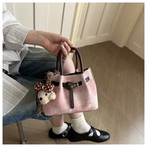 Close-up of pink checkered bucket bag with cute bear charm and brown handles