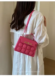 Fashionable hot pink crossbody bag with minimalist 3D circle design on white coat