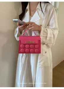 Close-up of a pink designer handbag with unique circular patterns held by a model