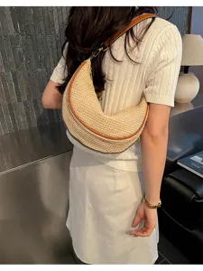 Femme portant un sac demi-lune en paille tressée élégant pour les vacances d'été à la plage