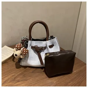 Detailed view of retro denim bucket bag set with brown leather handles and pouch.