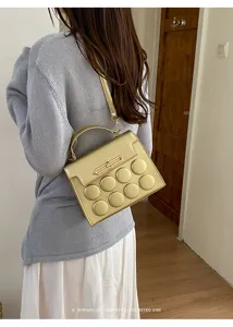 Champagne gold small square handbag with 8 circular padded details shown on model back