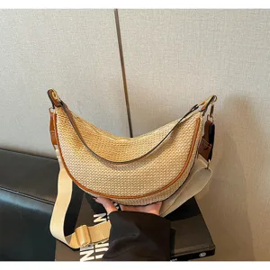 Gros plan d'un sac demi-lune en paille tressée avec une large bandoulière en toile.