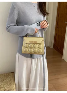 Close-up of a minimalist gold handbag with unique circular embossed design