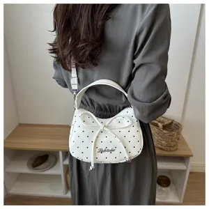 Stijlvolle witte maanvormige crossbodytas met stippen en strik gedragen door model.