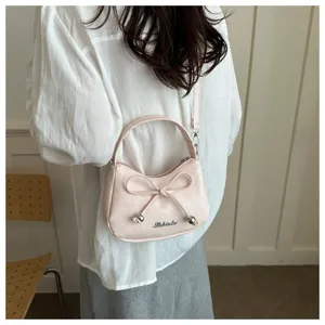 Roze maanvormige tas met witte stippen en strikdetail, gedragen als crossbody