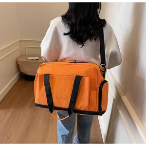 Detailed view of large capacity orange travel duffel bag with black straps for short trips.