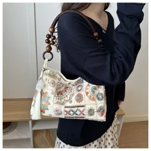 Dettaglio di una borsa tote ricamata in stile cinese con manico in legno e nappa.